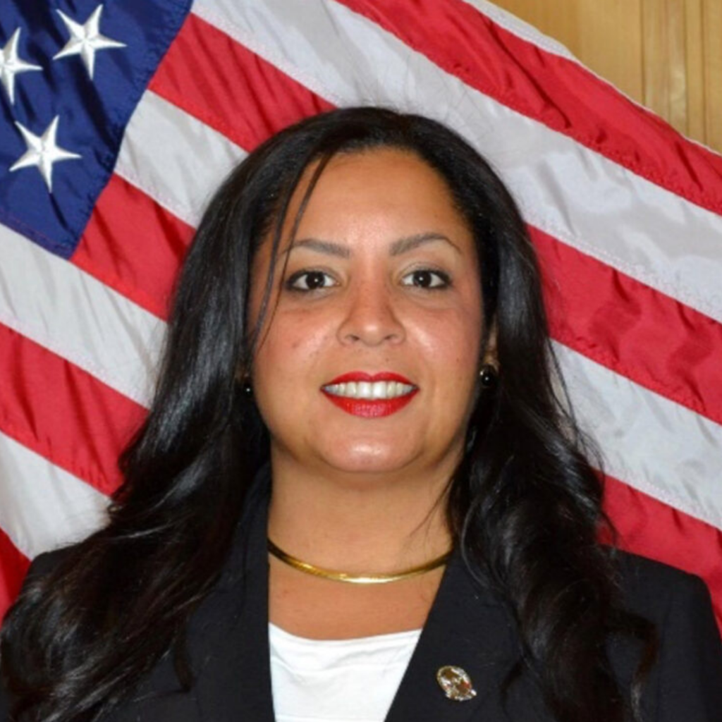 Grisel Velazquez smiles in front of an American flag